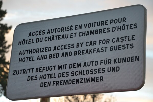 A sign with text in multiple languages about authorized car access for hotel and breakfast guests.