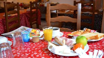 A breakfast table with various food items and a newspaper.