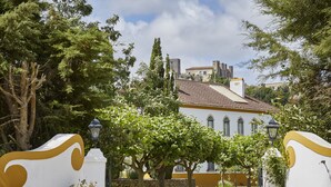 A building with a yellow facade, a tiled roof, and a stone wall in the foreground. - Casa d'Óbidos (Obidos)