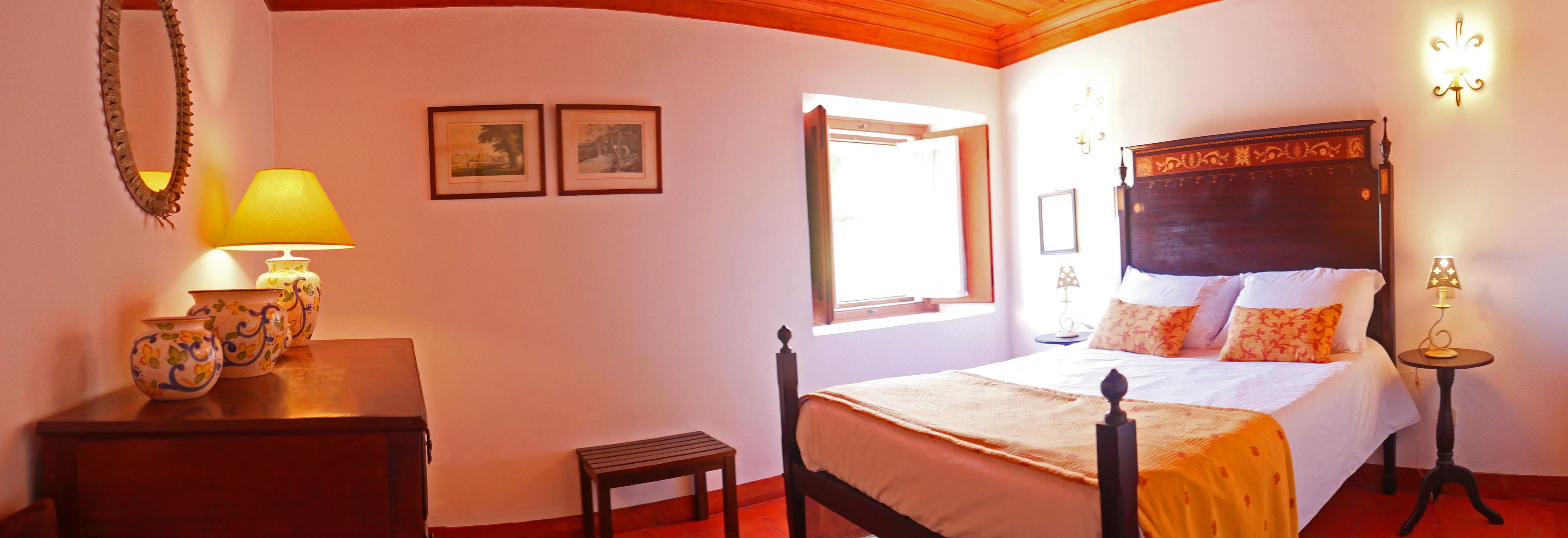 A bedroom with a bed, bedside tables, a lamp, a chest of drawers, and framed pictures on the wall.
