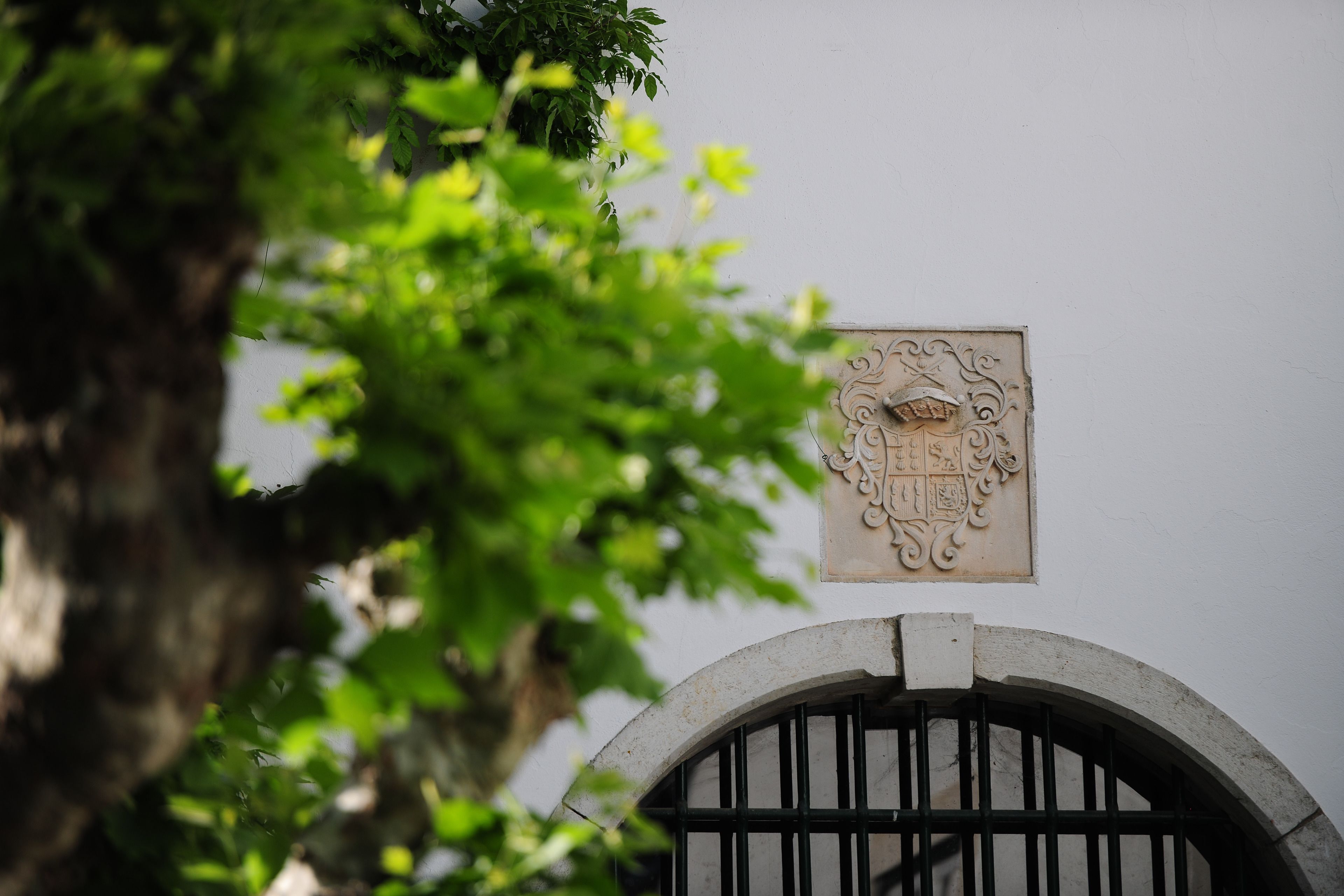 A white wall with a decorative plaque and a black metal gate.