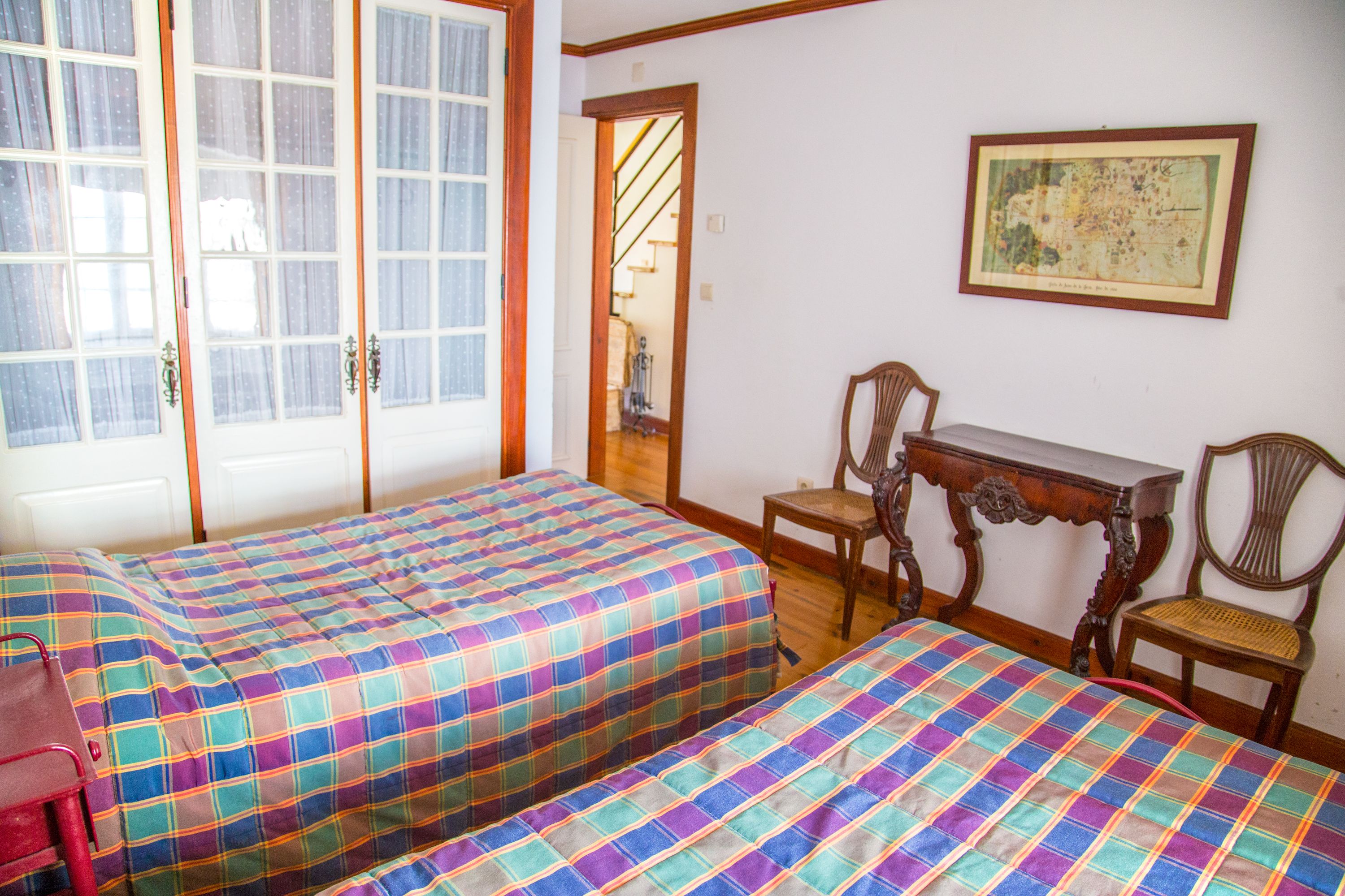 Una habitación con dos camas, un escritorio y sillas.