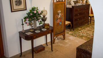 A room with a wooden desk, a vase with flowers, a framed picture, and a dresser with a mirror.
