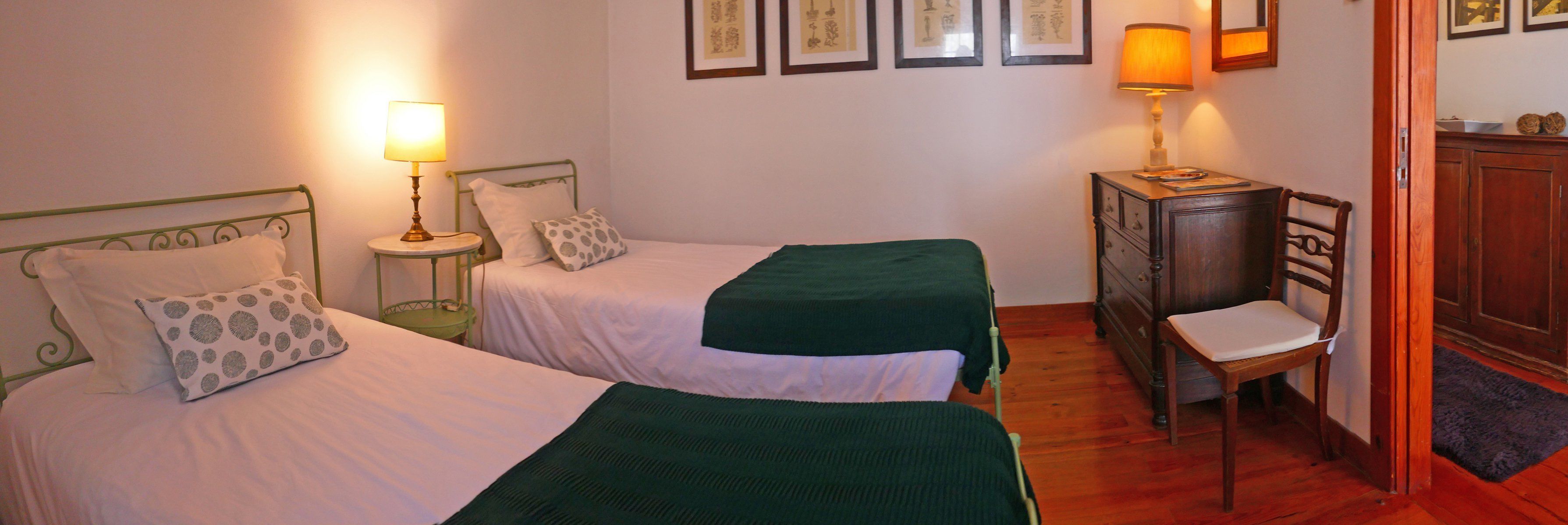 A room with two single beds, a chair, a small table, and a cabinet.
