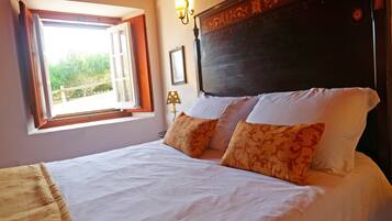 A bedroom with a bed, a window, a wall-mounted lamp, and a headboard.