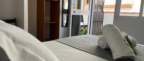 A hotel room with a bed, a wooden wardrobe, and a view of the outside.