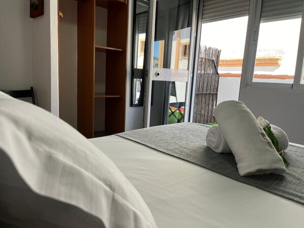 A hotel room with a bed, a wooden wardrobe, and a view of the outside.