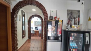 A hallway with a brick archway, a vending machine, and a refrigerator. - Orfebre Góngora (Córdoba)