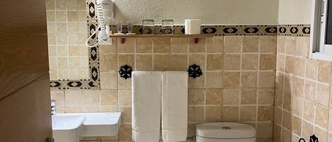 Un baño con bidé, inodoro, lavamanos y azulejos decorativos.
