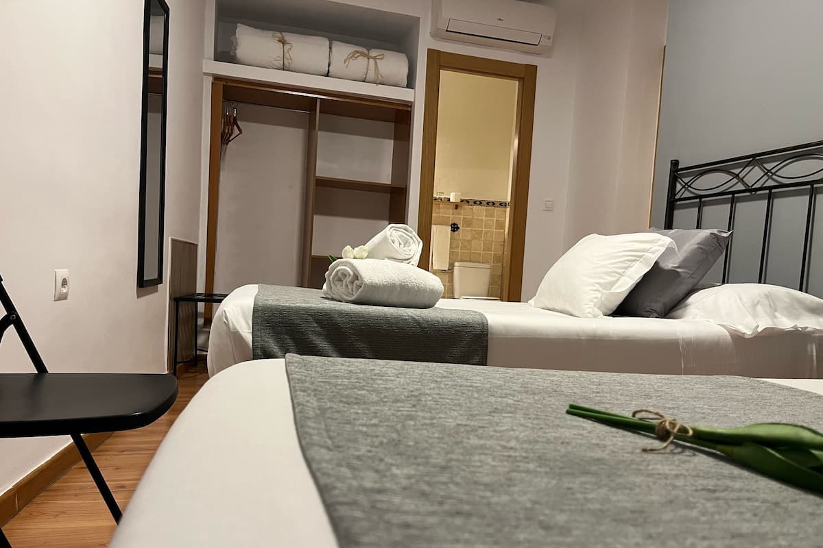 Una habitación de hotel con cama, una silla, armario y baño.