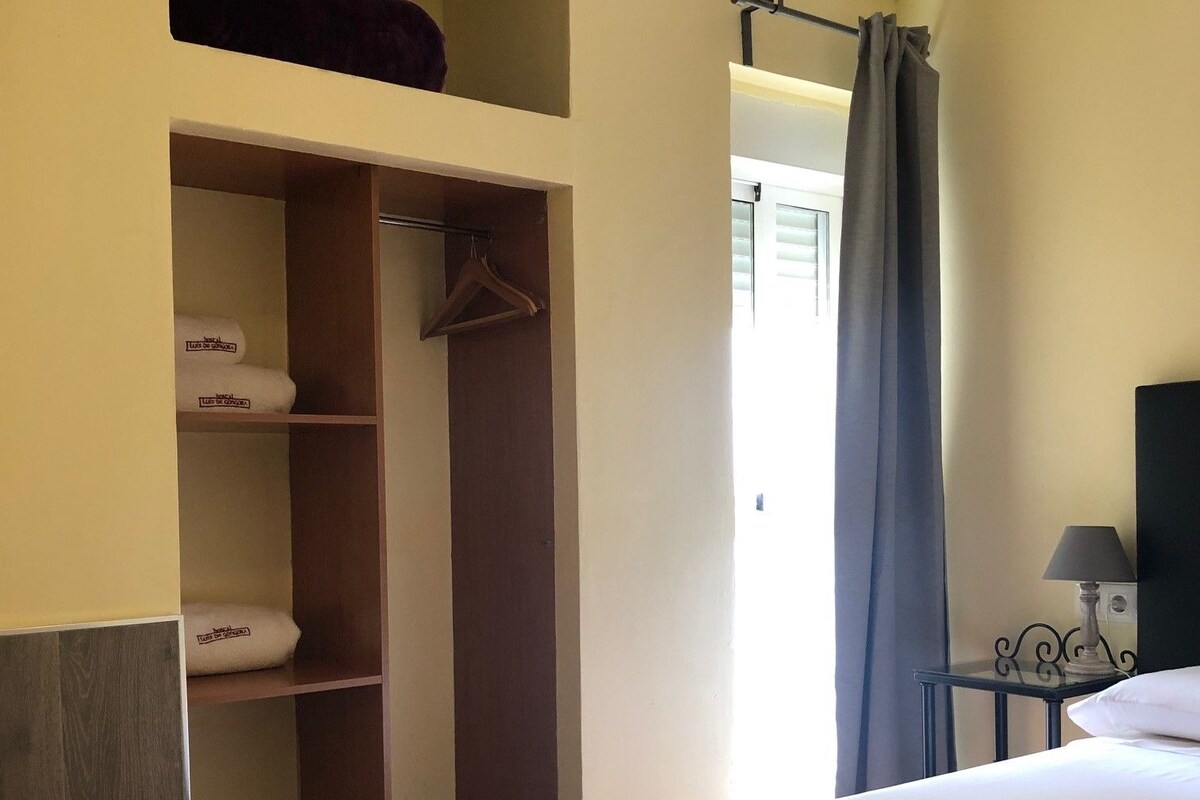 A hotel room with a bed, a wardrobe, a desk, and a nightstand.