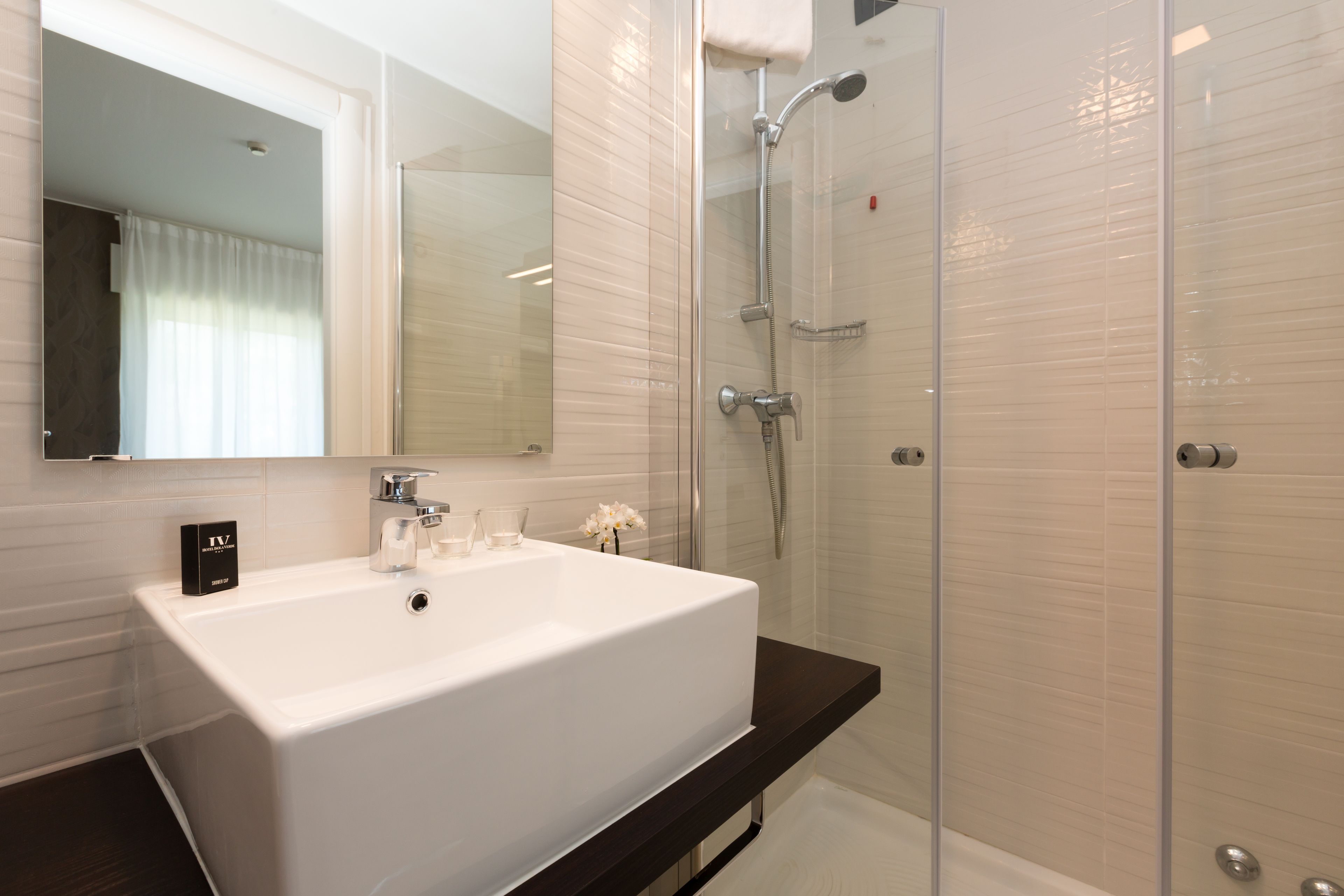 Un baño moderno con un lavamanos grande de color blanco, una cabina de ducha de vidrio y una encimera oscura.