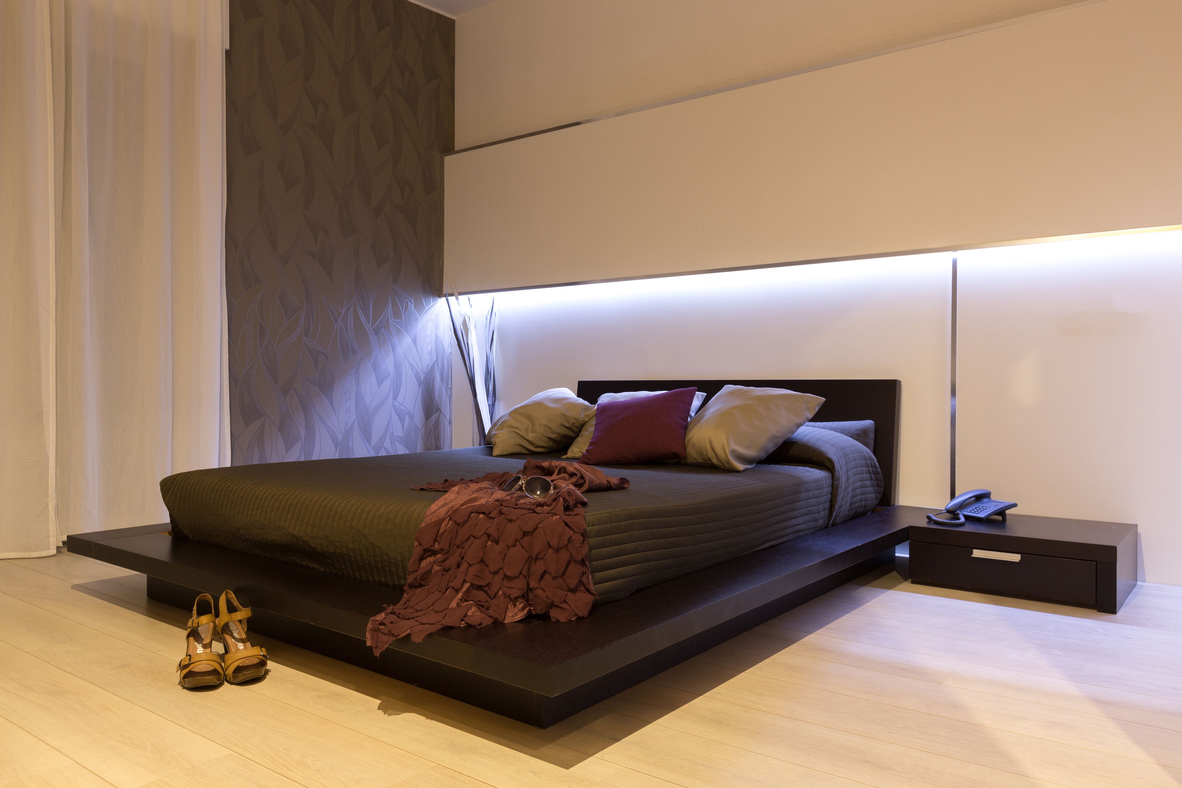 Un dormitorio moderno con una cama grande, una mesita de noche y una mesita auxiliar.