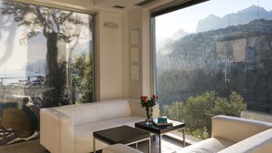 Un saló modern amb un sofà blanc, una taula de centre i vista als muntanyes a través de grans finestres.