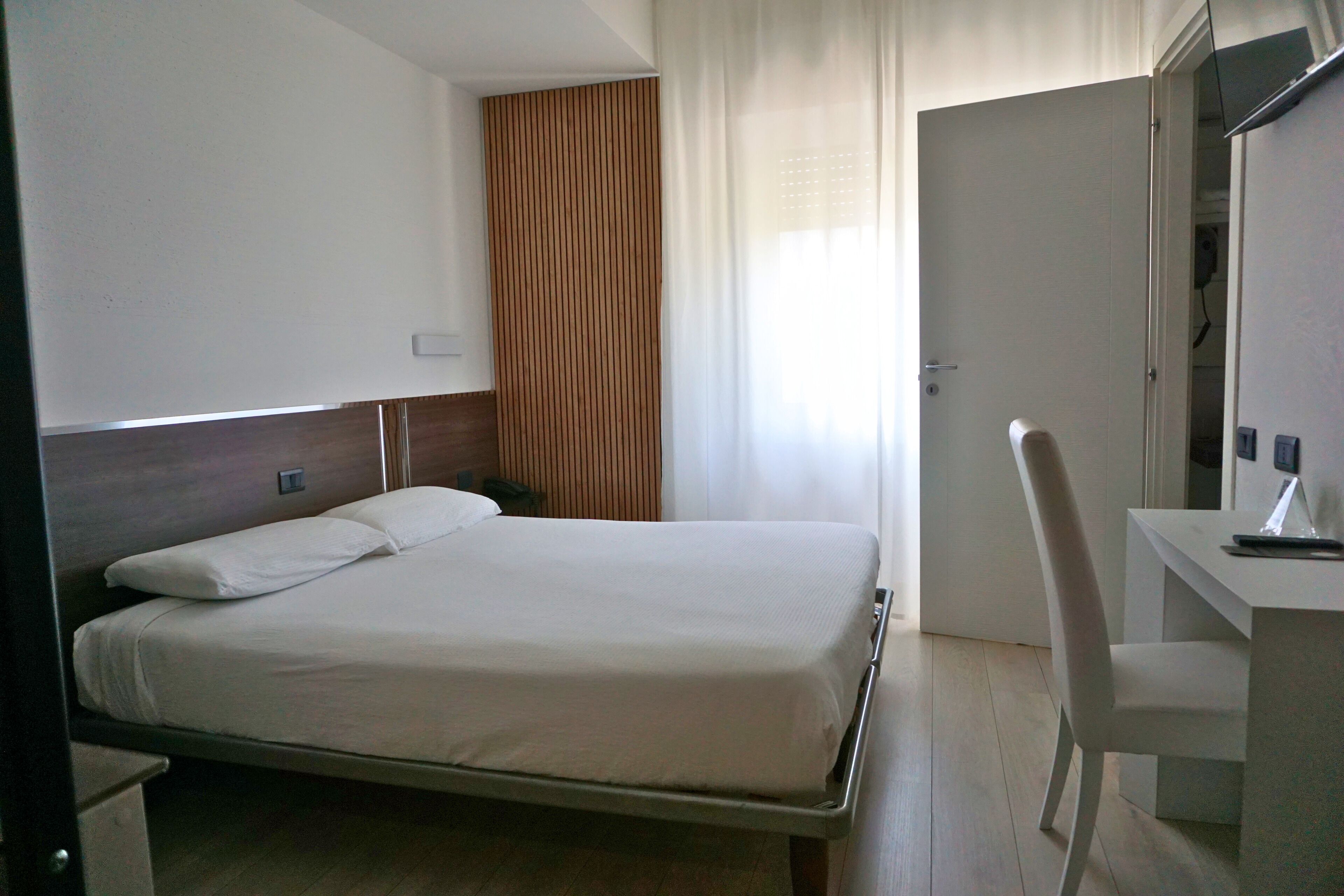 A hotel room with a bed, a desk, and a chair.