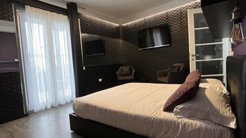 Un dormitorio moderno con una cama grande, un televisor de pantalla plana, un armario y una puerta corrediza de vidrio.