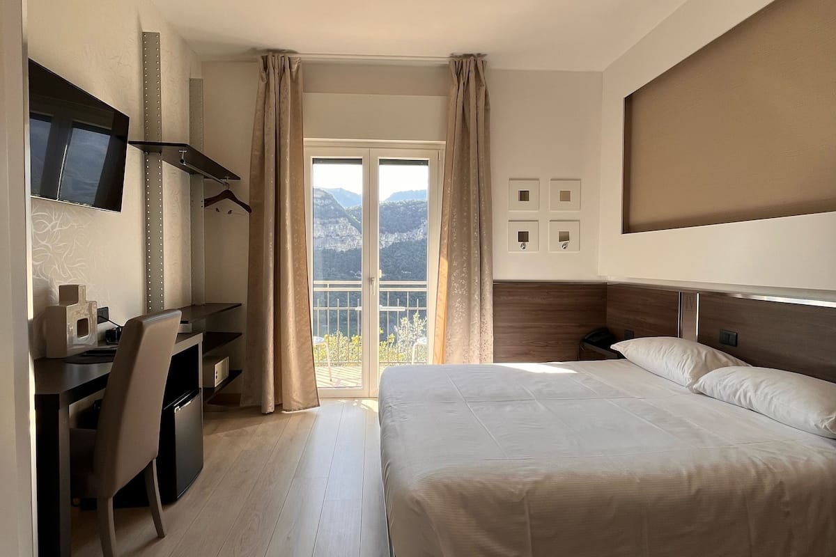 A hotel room with a bed, desk, and a TV mounted on the wall.