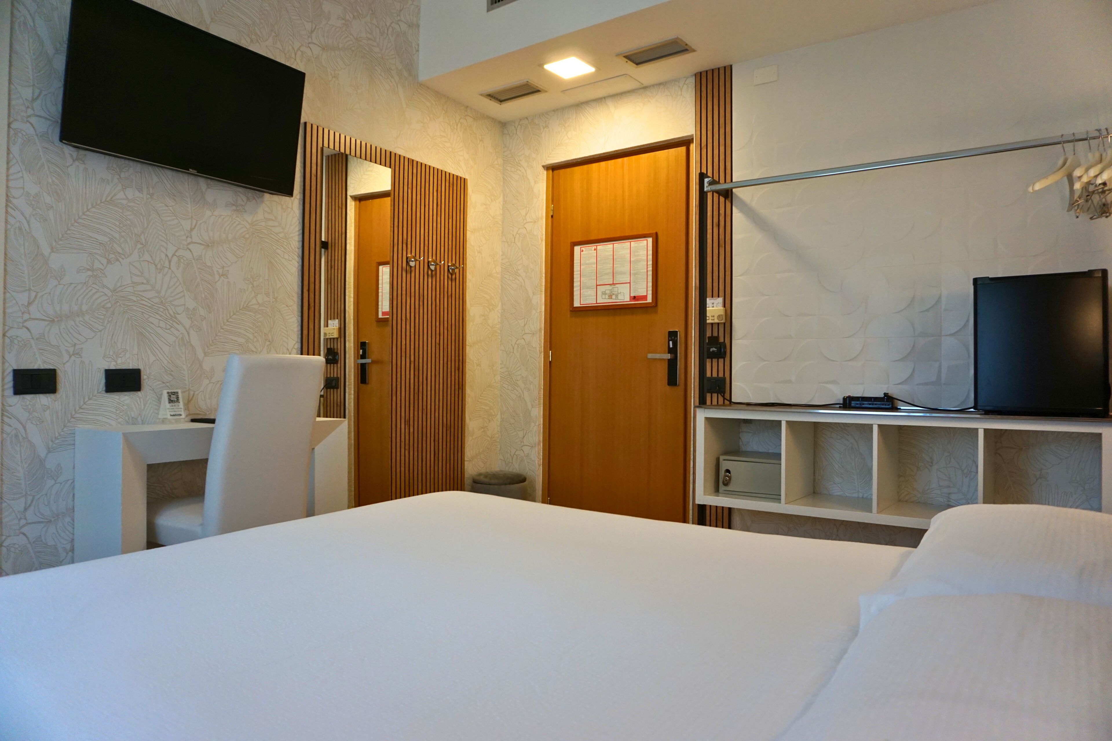 Ein Hotelzimmer mit einem Bett, einem Schreibtisch, einem Stuhl, einem Fernseher und einem Kleiderschrank.