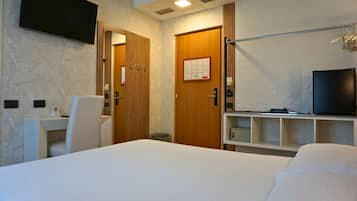Ein Hotelzimmer mit einem Bett, einem Schreibtisch, einem Stuhl, einem Fernseher und einem Kleiderschrank.