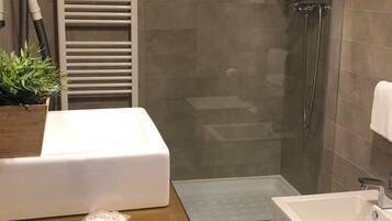 Un baño moderno con ducha de vidrio, lavamanos blanco y bañera.