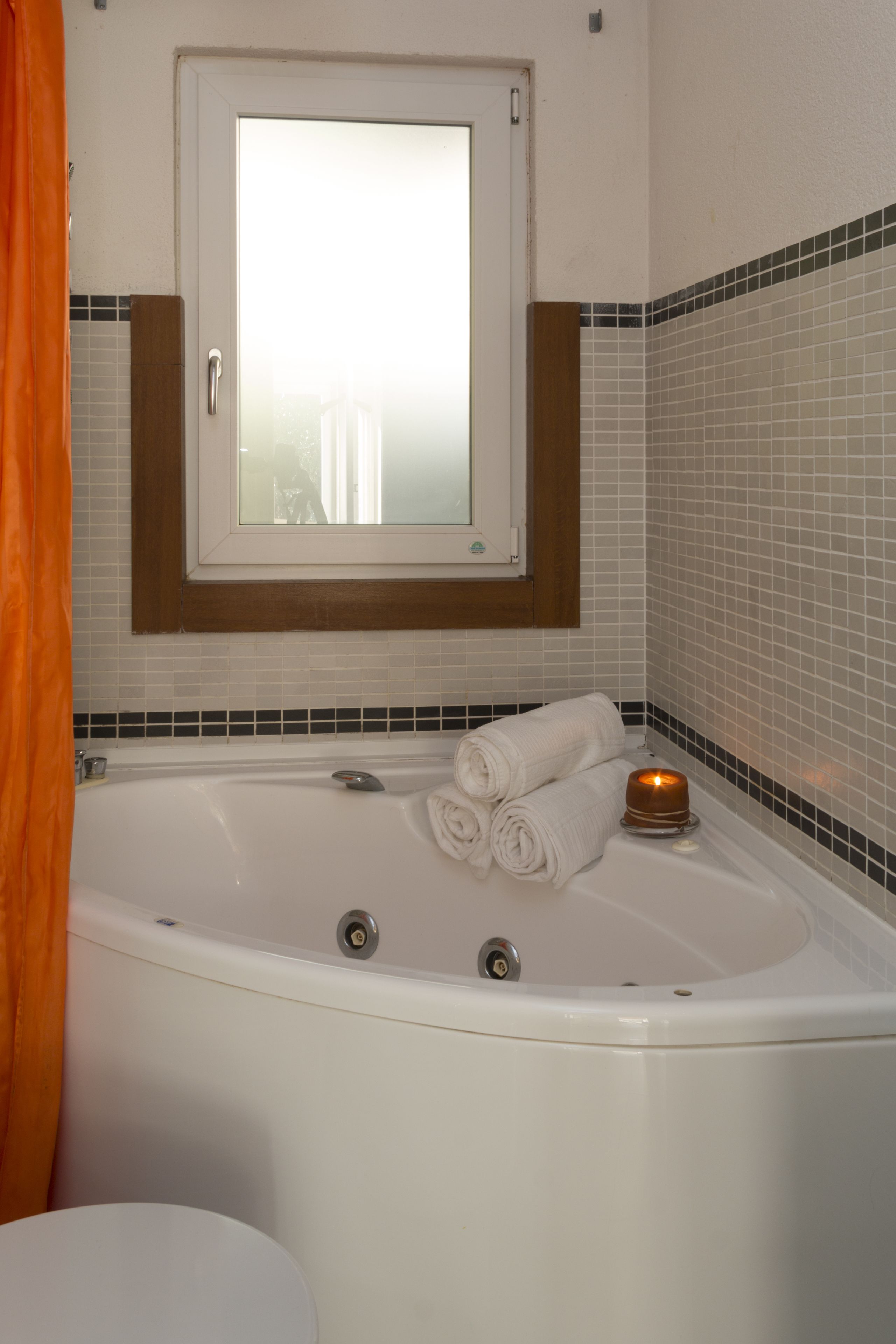Ein Badezimmer mit Badewanne, einem Fenster darüber und einem Handtuchhalter mit Handtüchern.