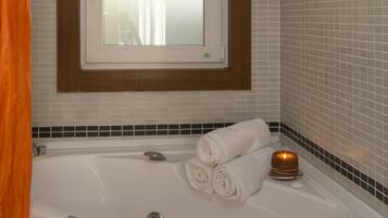 Ein Badezimmer mit Badewanne, einem Fenster darüber und einem Handtuchhalter mit Handtüchern.