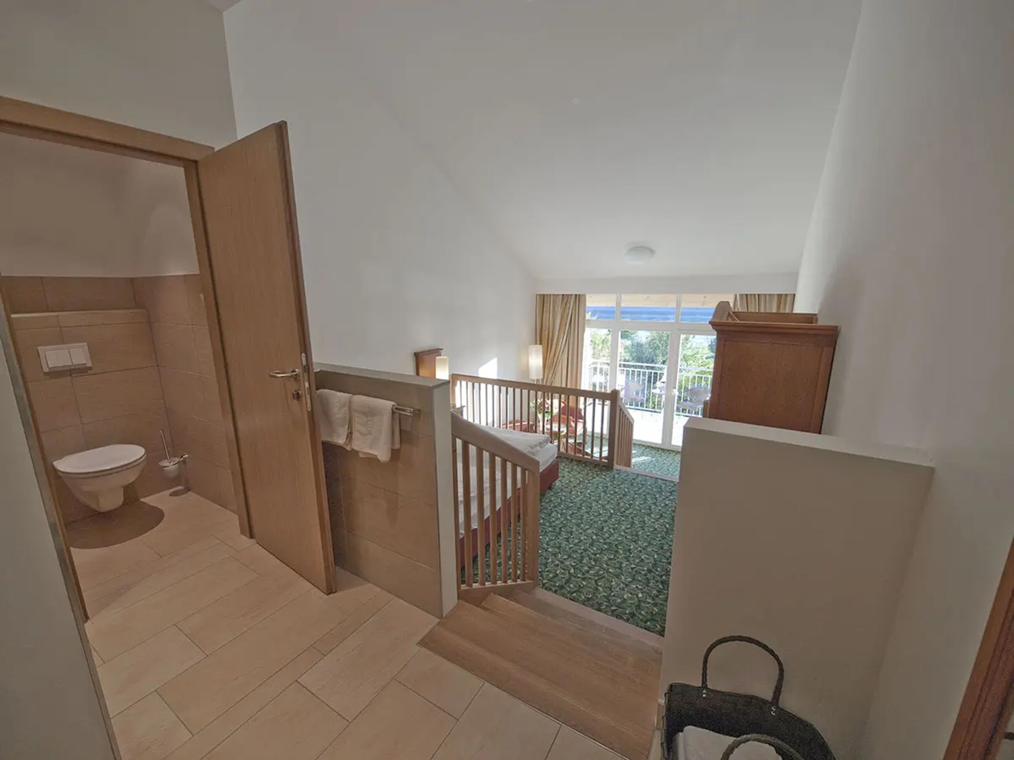 Una habitación de hotel con baño, un balcón con vistas y una escalera.