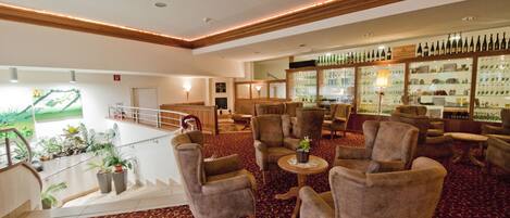 A spacious lobby with a bar area, multiple seating options, and a view of a golf course.