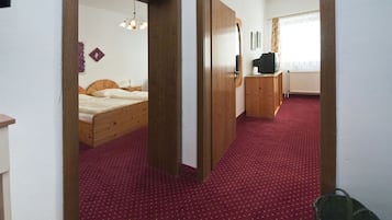 A bedroom with a wooden bed, a red carpet, and a wooden wardrobe.