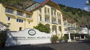 A hotel with a yellow facade, multiple balconies, and a sign indicating it offers wellness services. - Gartenhotel & Weingut Pfeffel Dürnstein (Durnstein)