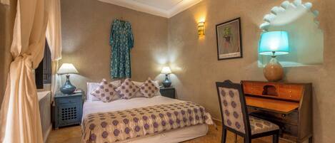 A bedroom with a bed, bedside tables, a desk, and a chair.