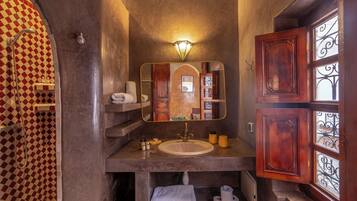 Un baño con pared de ducha a cuadros, un espejo grande, un lavabo y armarios de madera.