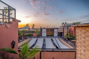 Terraza en la azotea con vistas a la puesta de sol, una pérgola y una valla de bambú.