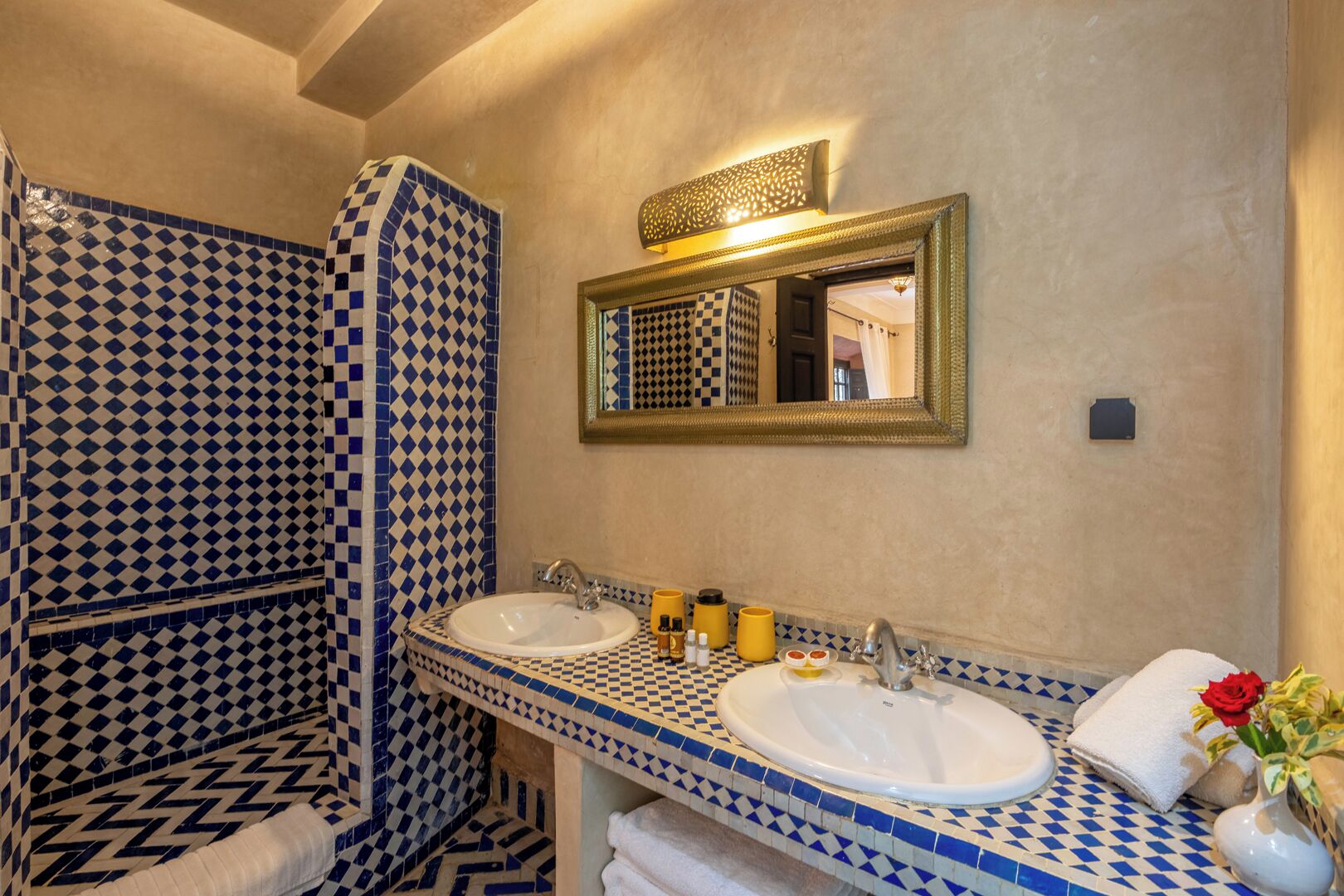 A bathroom with two sinks, a shower with checkered tiles, and a mirror with a decorative frame.