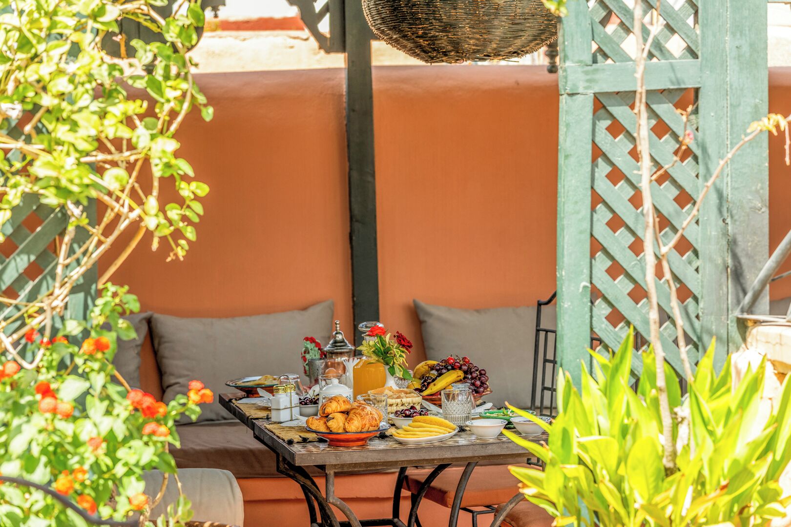 An outdoor dining area with a table set for breakfast, including fruits, pastries, and beverages.