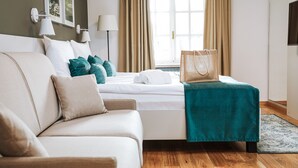 A hotel room with a bed, a sofa, a window with curtains, a lamp, and a bag on the bed. - Depandance Vila Higiea - Terme Dobrna (Dobrna)