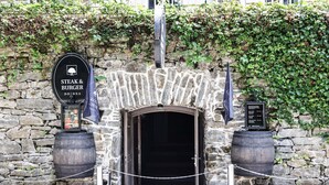 A stone archway entrance to a restaurant named "Steak & Burger" with a menu displayed on a stand. - Depandance Vila Higiea - Terme Dobrna (Dobrna)