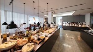 A buffet setup with various food items and beverages, a modern kitchen area in the background, and a clean, spacious layout. - Depandance Vila Higiea - Terme Dobrna (Dobrna)