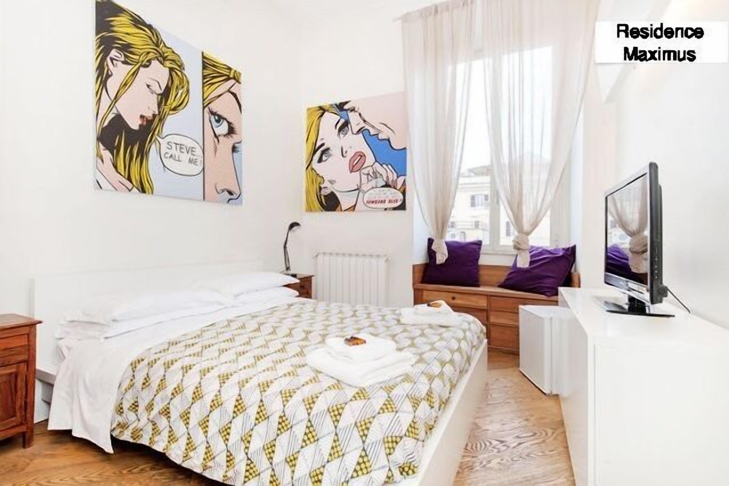 Un dormitorio con cama, televisor y obras de arte en la pared.