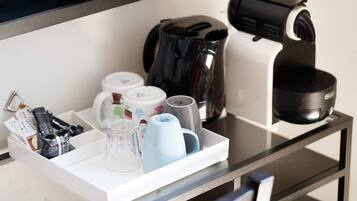 Una encimera de cocina con cafetera, hervidor y máquina de café.