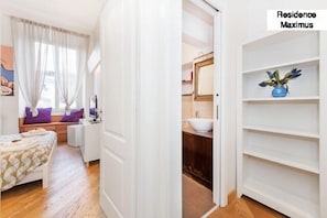 A bedroom with a bed, a window with curtains, a bedside table, and a wall-mounted TV. - Maximus (Rome)