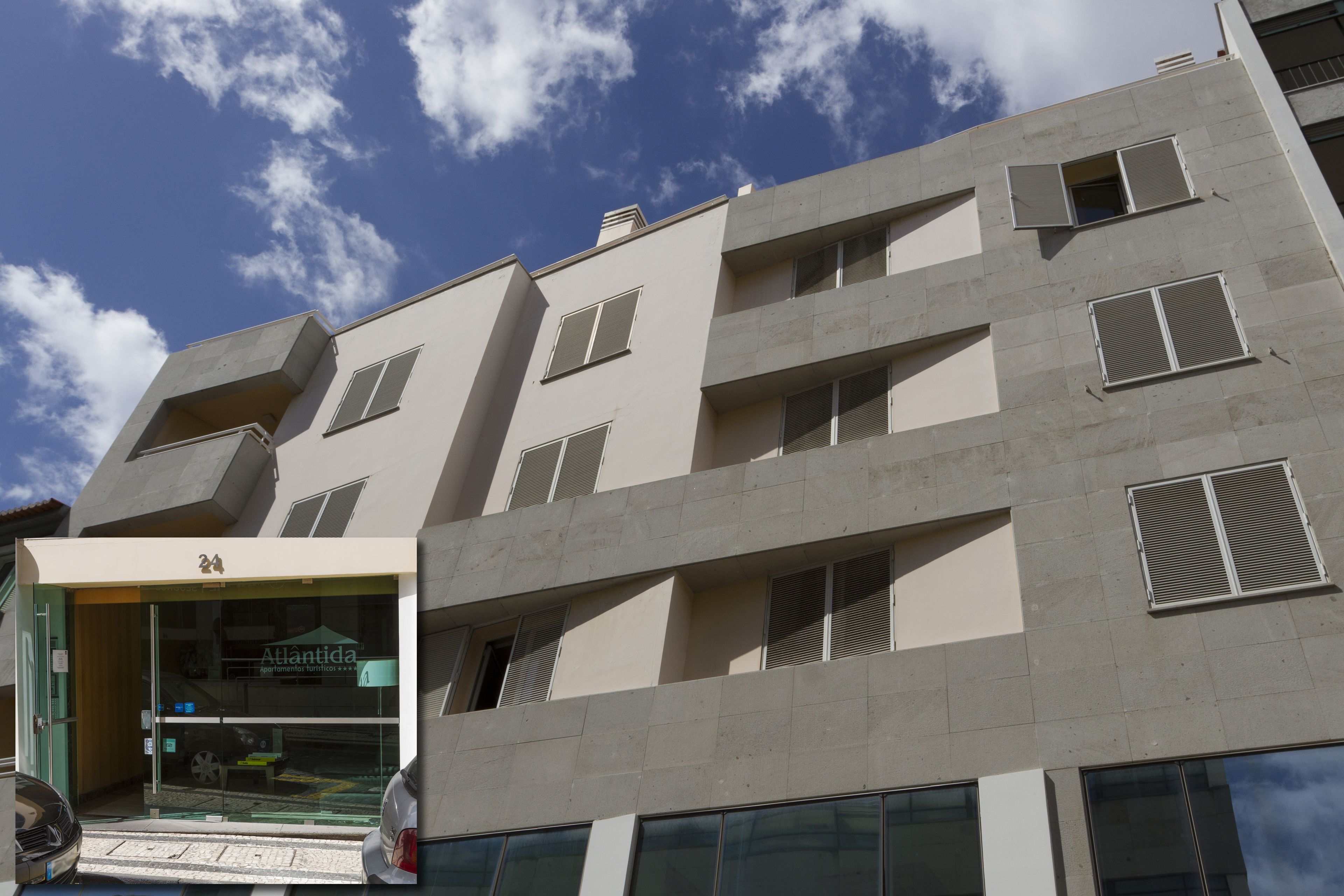 A multi-story building with a flat facade, several windows, and a ground-level entrance with a glass door.