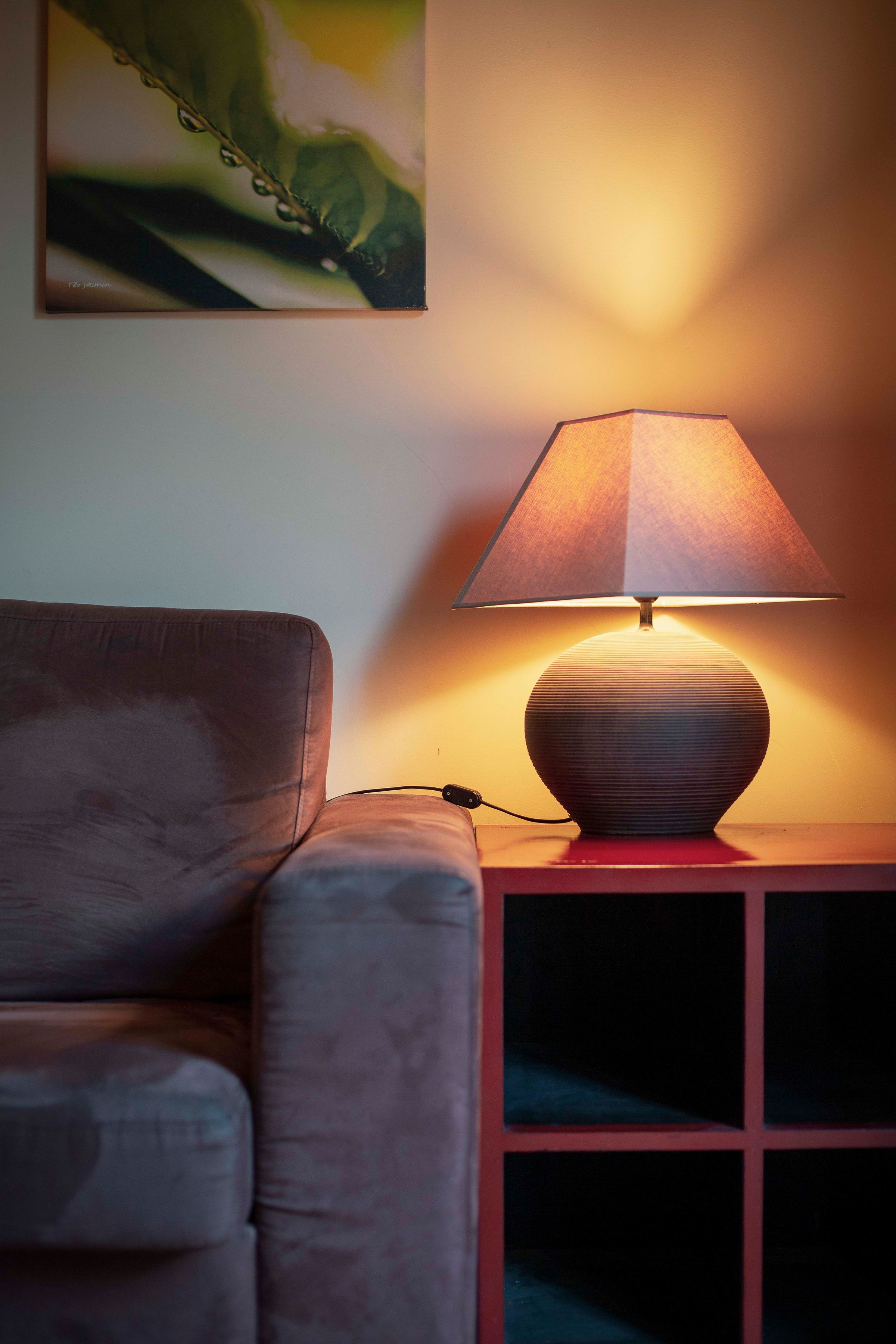 Eine Lampe auf einem Nachttisch neben einer Couch.