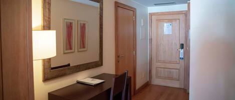 Un pasillo con un escritorio de madera, un espejo y una puerta.