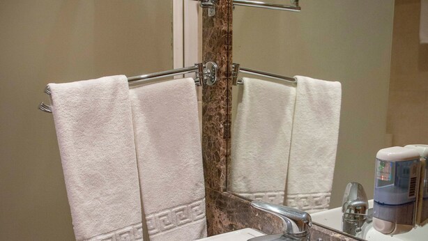 Une salle de bain avec un lavabo blanc, un miroir et deux serviettes suspendues à un porte-serviettes.