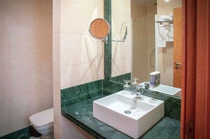A bathroom with a white sink, a round mirror, and a toilet.