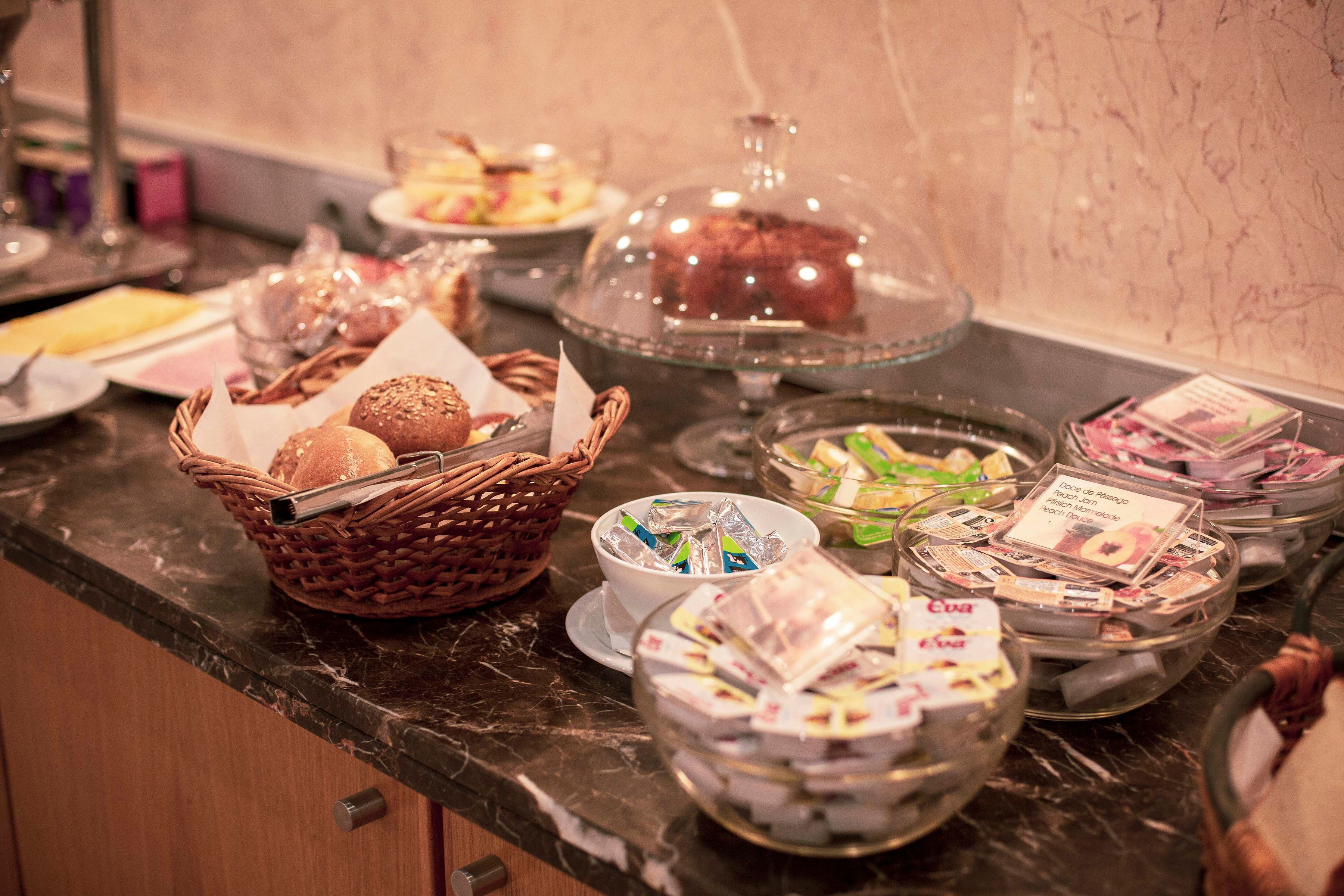 A buffet with various food items and a basket of bread.