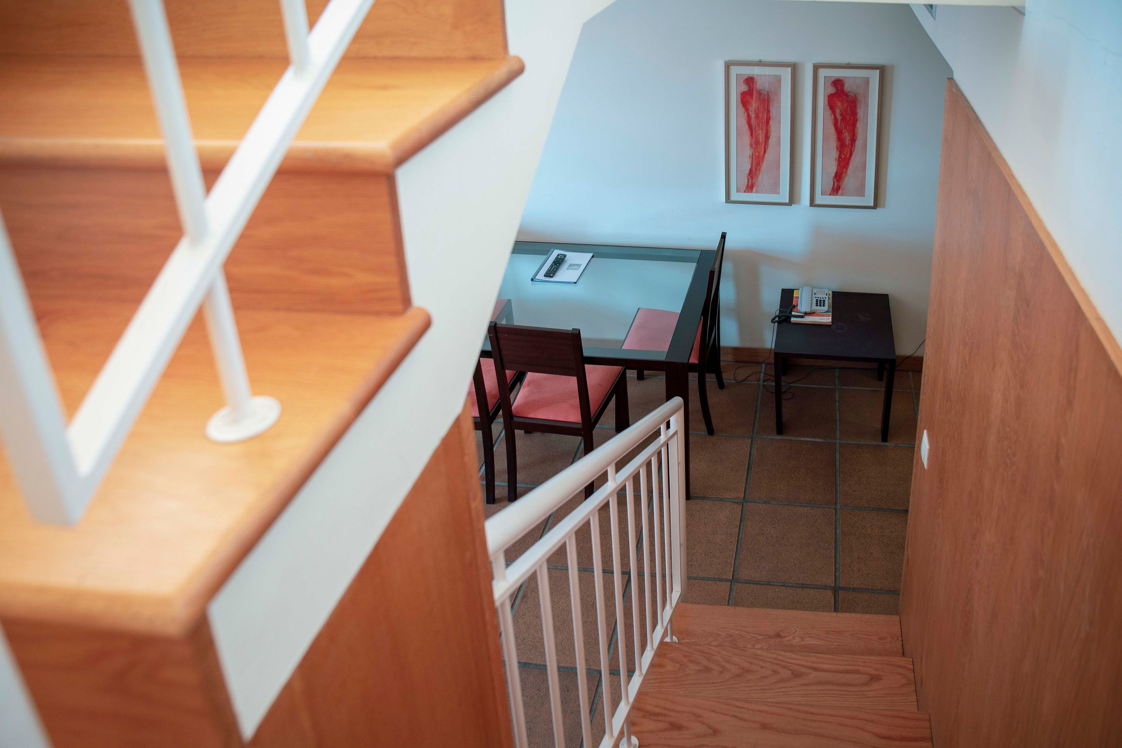 A staircase leading to a dining area with a table, chairs, and a small table with a telephone.
