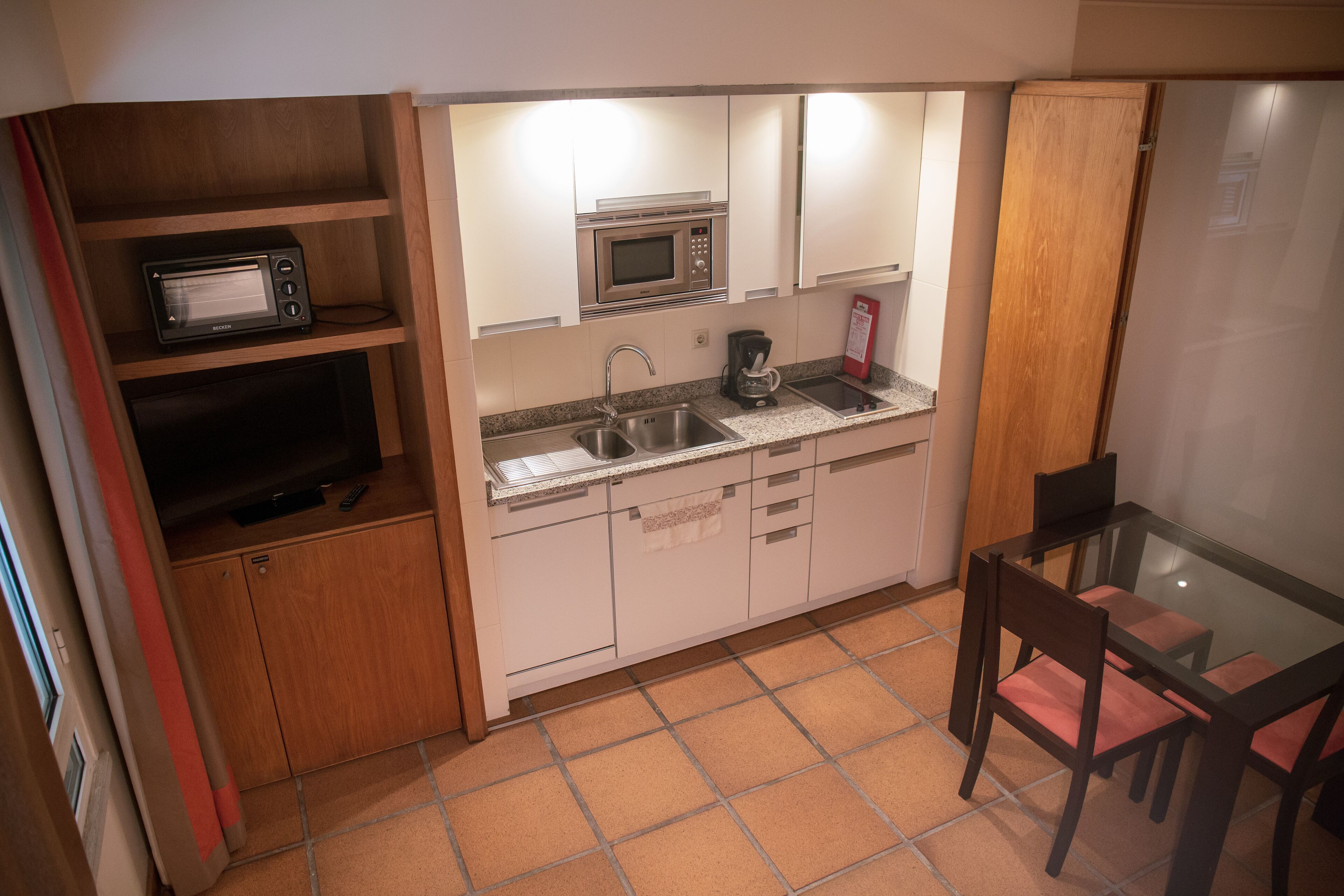 A compact kitchen with a microwave, coffee maker, and a small sink.