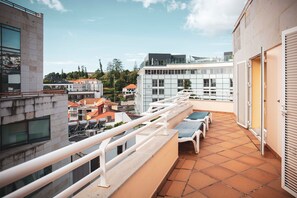 A rooftop terrace with a railing, a seating area with a table and chairs, and a view of surrounding buildings. - Apartamentos Turisticos Atlantida (Funchal)